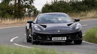 Lotus Emira (2023): front cornering, showing (some) body roll, black paint, country lane